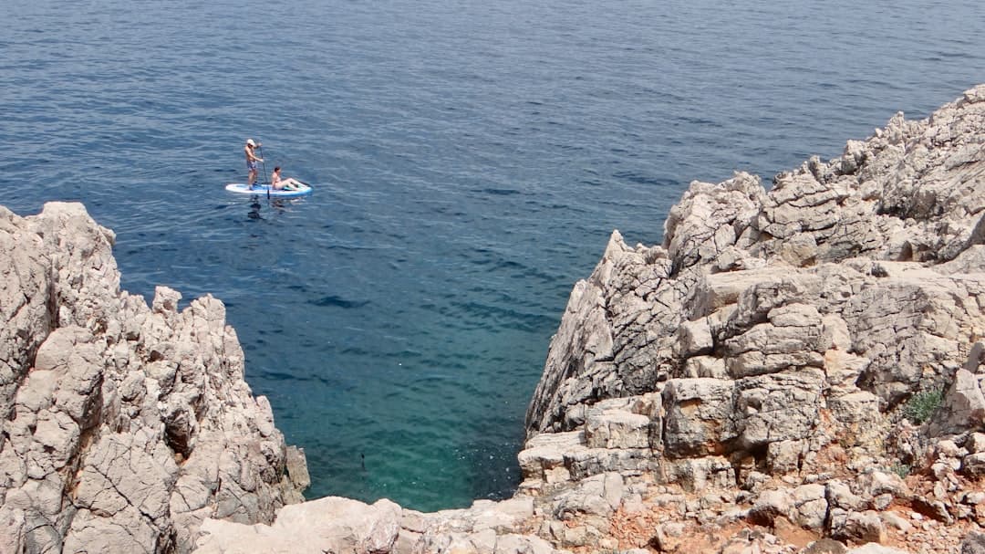 Paddleboarding na morzu przy skalistej plaży