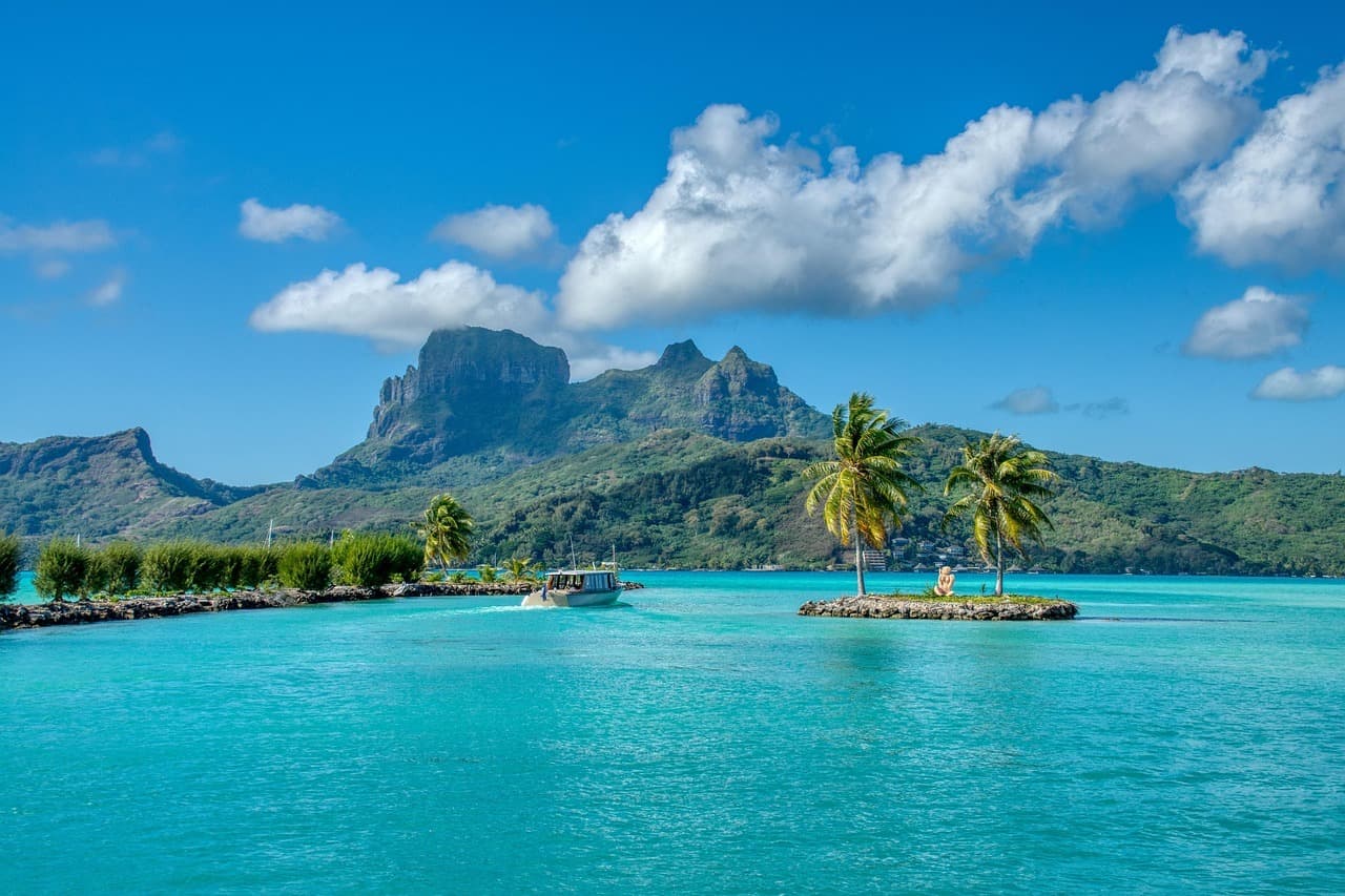 Turkusowa laguna Bora Bora z górami, palmami i łodzią
