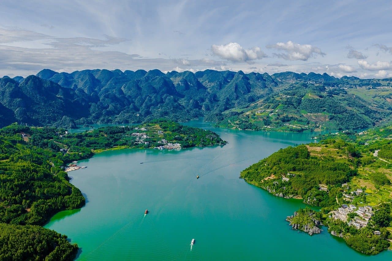 Malownicze turkusowe jezioro otoczone zielonymi górami krasowymi z wioskami.