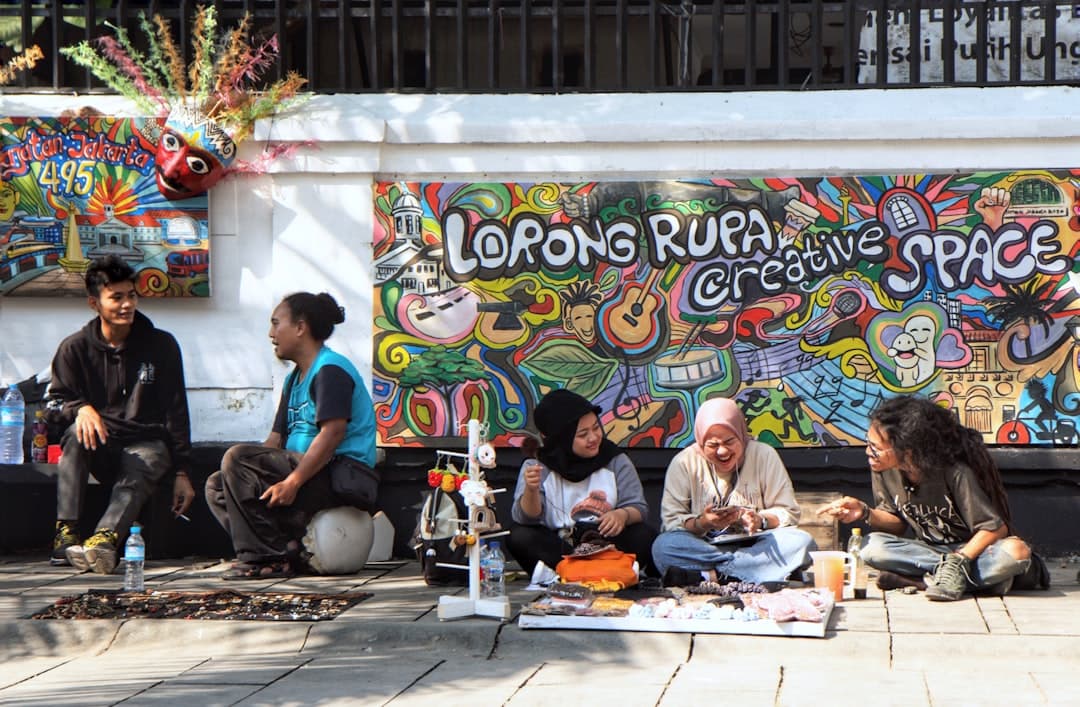 Grupa ludzi przy kolorowym muralu ulicznym.