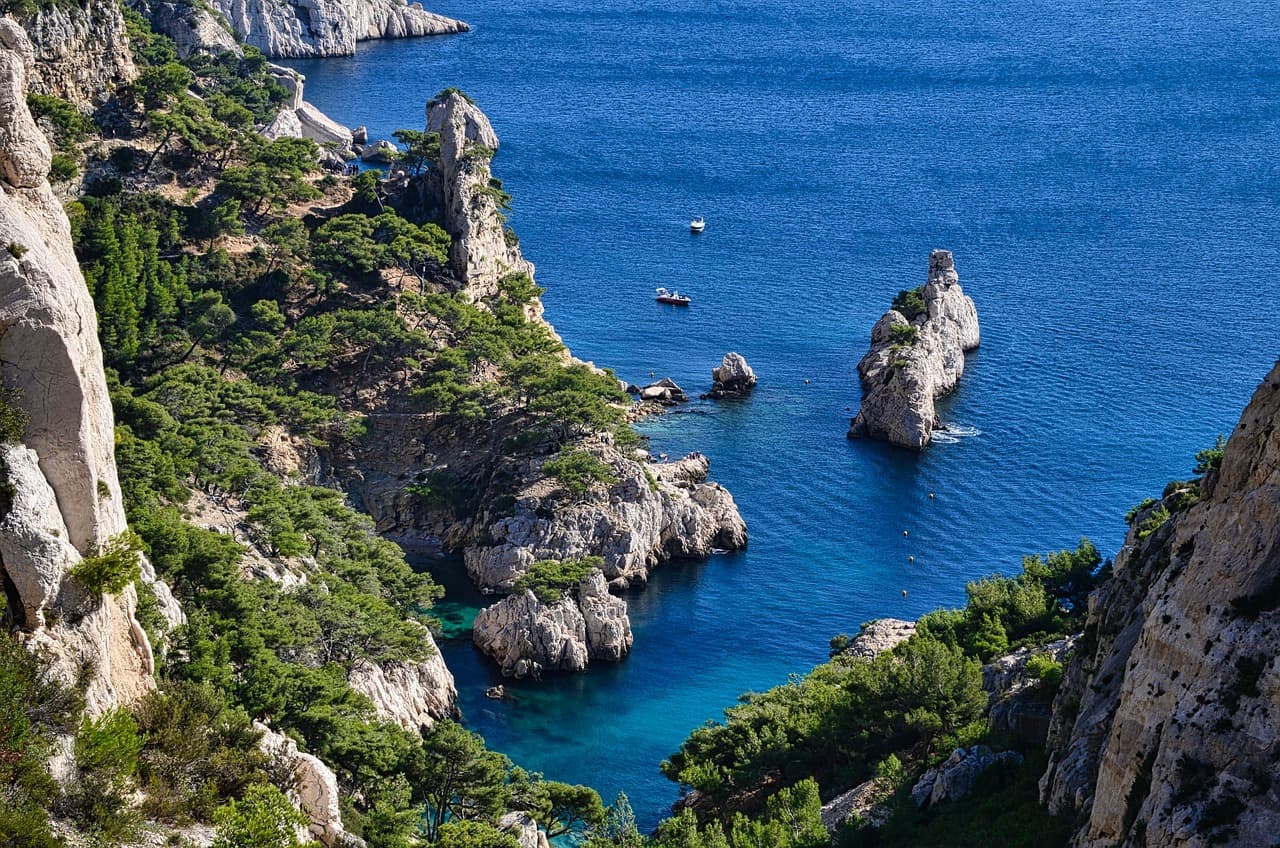 Calanques, skaliste klify, sosny, turkusowe morze, łodzie, krajobraz śródziemnomorski.