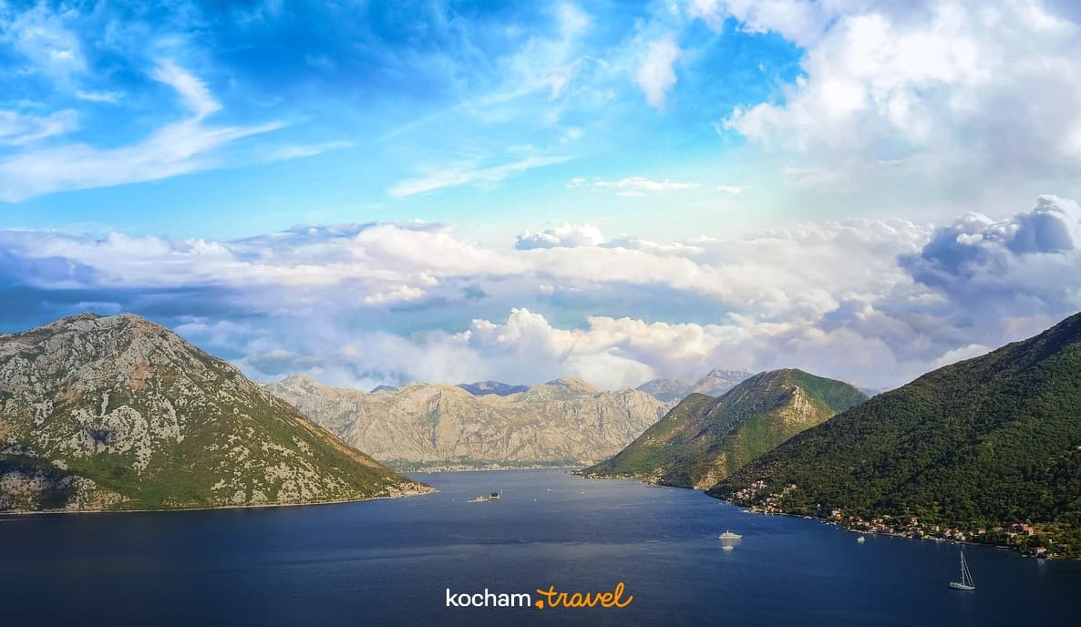 Panoramiczny widok zatoki otoczonej górami, z łodziami na wodzie.