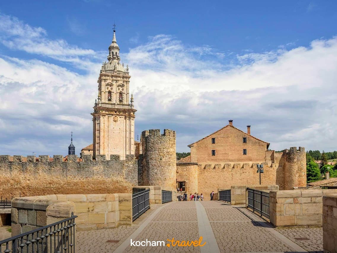 Starożytna wieża, mury obronne, zabytkowy budynek, turyści, słoneczny dzień.