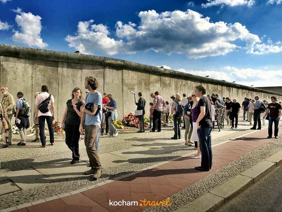 Turyści oglądający historyczny Mur Berliński w słoneczny dzień