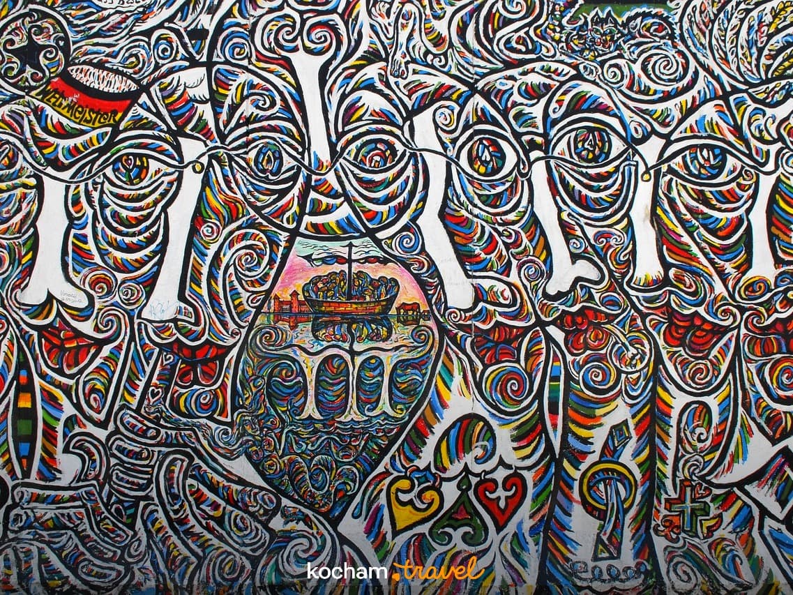 Kolorowy, abstrakcyjny mural na murze berlińskim, łódź, ludzie.