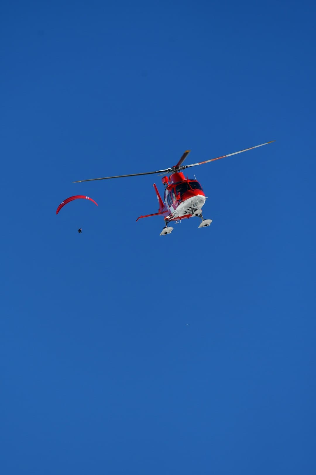 Helikopter i paralotniarz na niebie.