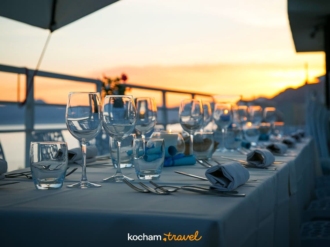 Elegancko zastawiony stół restauracyjny na tarasie o zachodzie słońca.