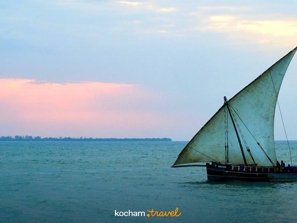 Tradycyjny żaglowiec dhow na turkusowym morzu o zachodzie słońca.