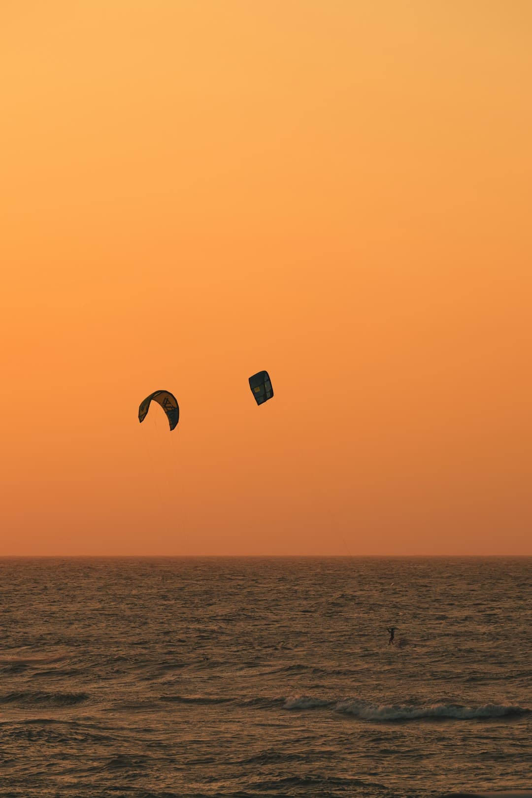 Kitesurferzy śmigający po falach o zachodzie słońca w Paje