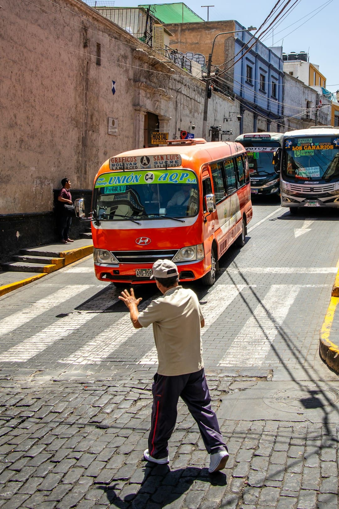 Mężczyzna na przejściu, ruchliwe ulice, autobusy miejskie.