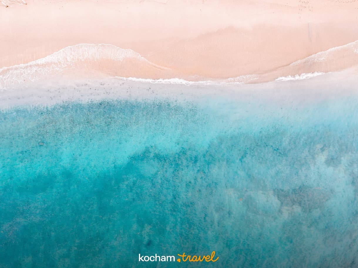 Turkusowa woda oceanu, piaszczysta plaża, fale z lotu ptaka.