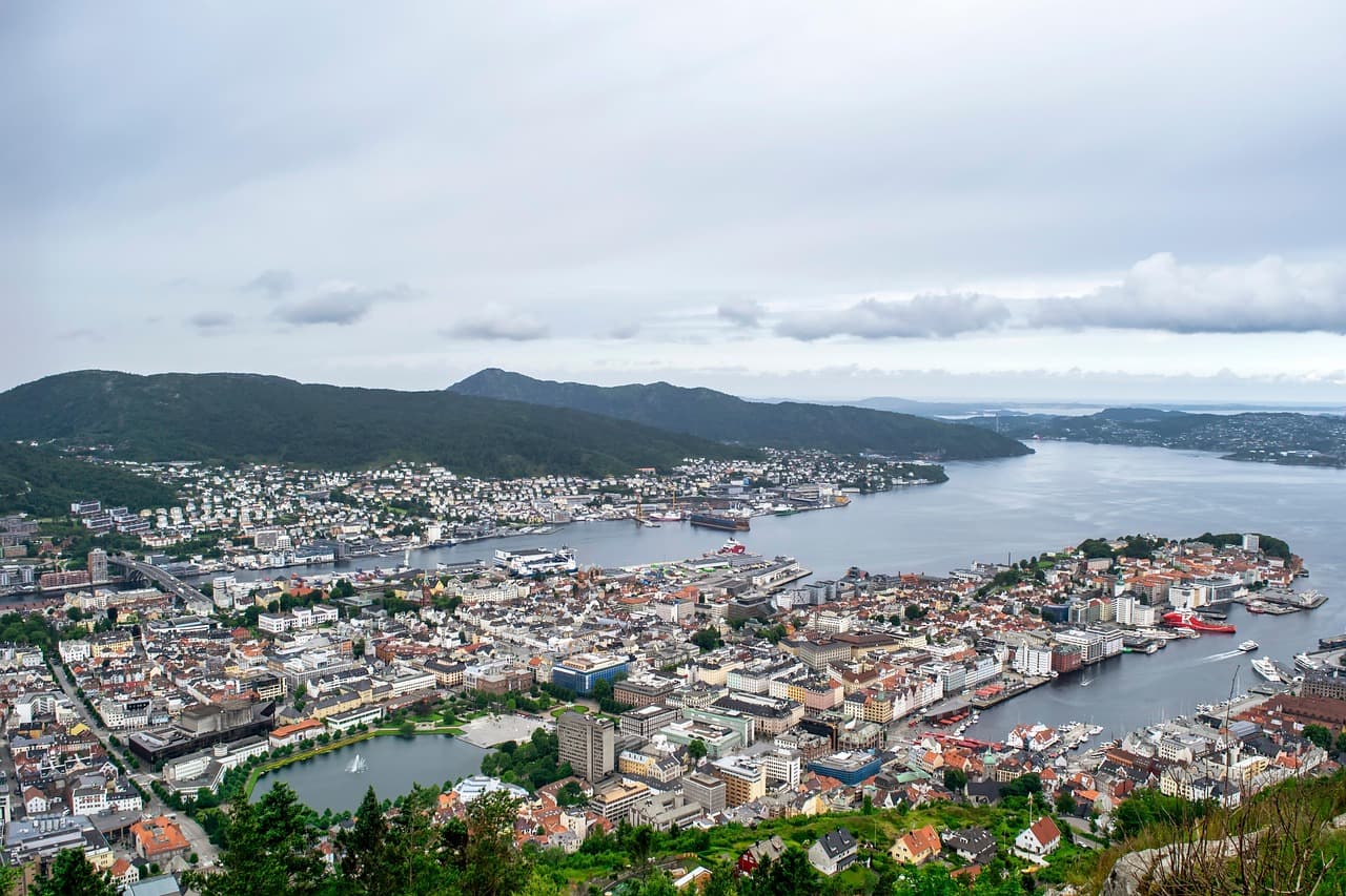 Bergen, Norwegia: miasto, góry, port, jezioro, budynki, pochmurne niebo.