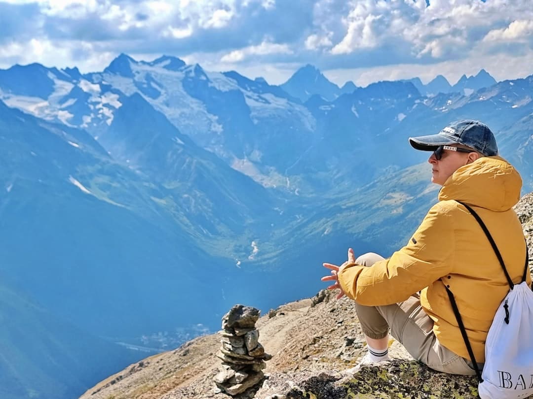 Osoba w kurtce patrzy na górskie szczyty.