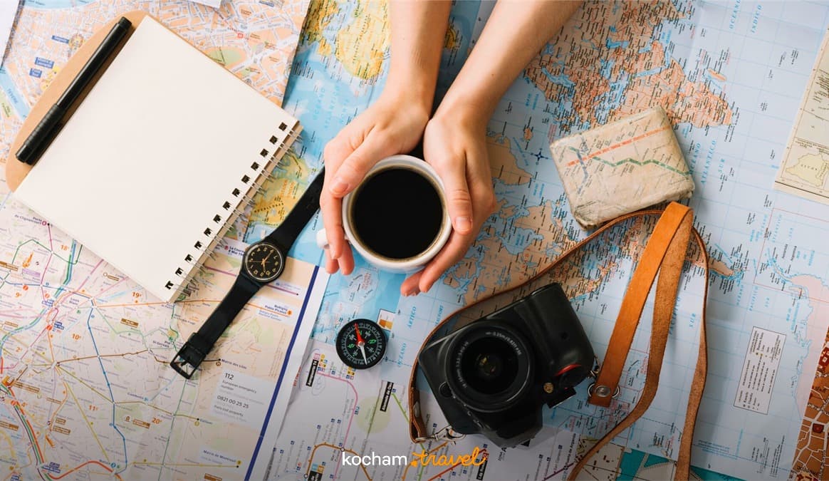 Planowanie podróży z kawą, mapami, notesem i aparatem fotograficznym.
