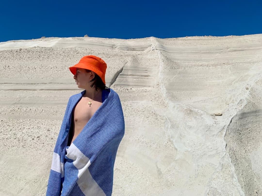 Osoba w pomarańczowym kapeluszu przed klifem