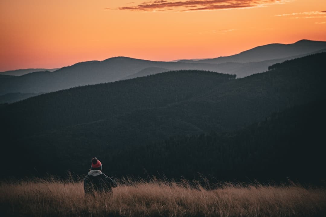 Wędrowiec cieszący się pięknym widokiem zachodu słońca w górach
