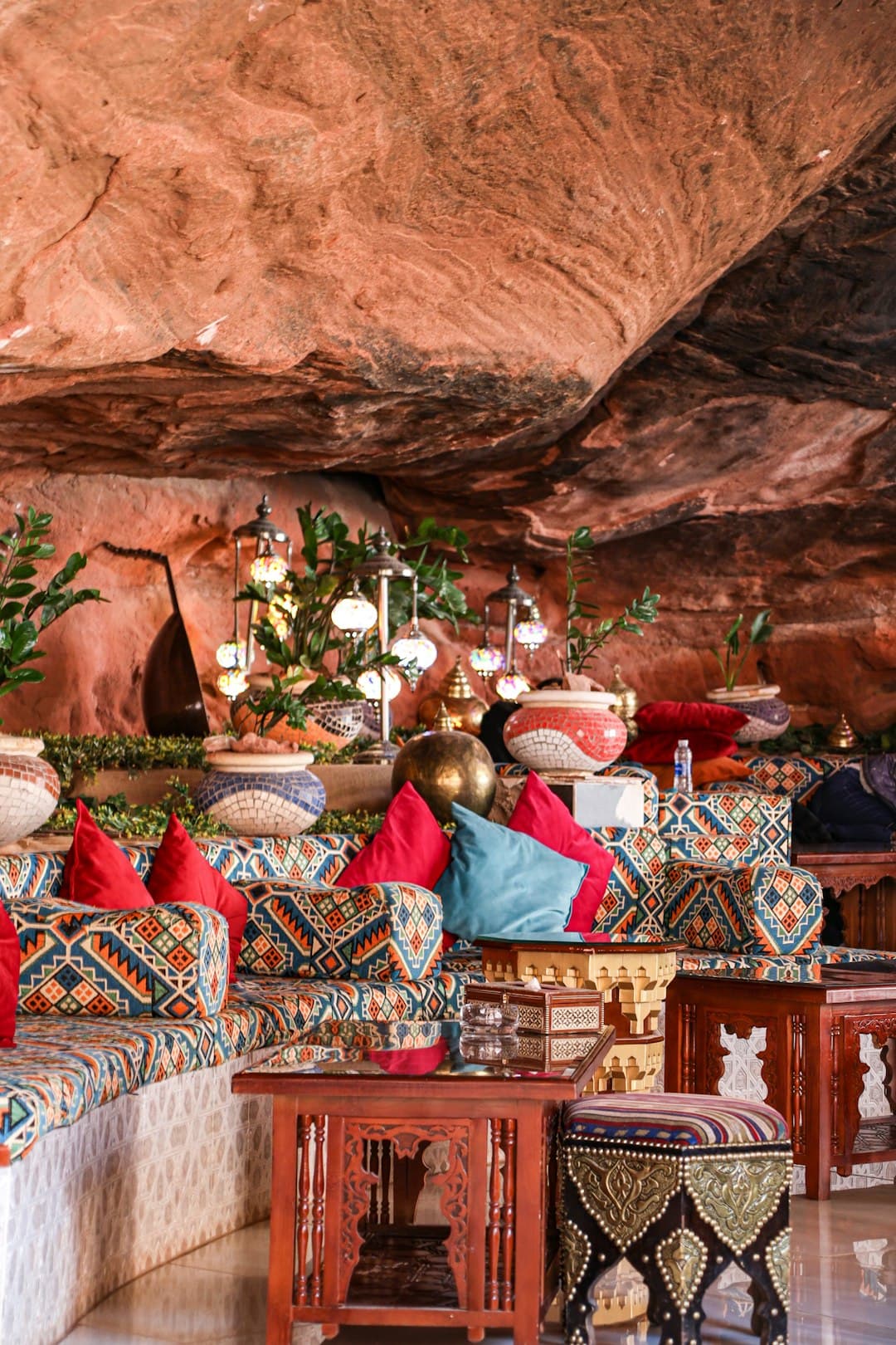 Stylowe wnętrze jaskini z kolorowymi tkaninami i lampionami.