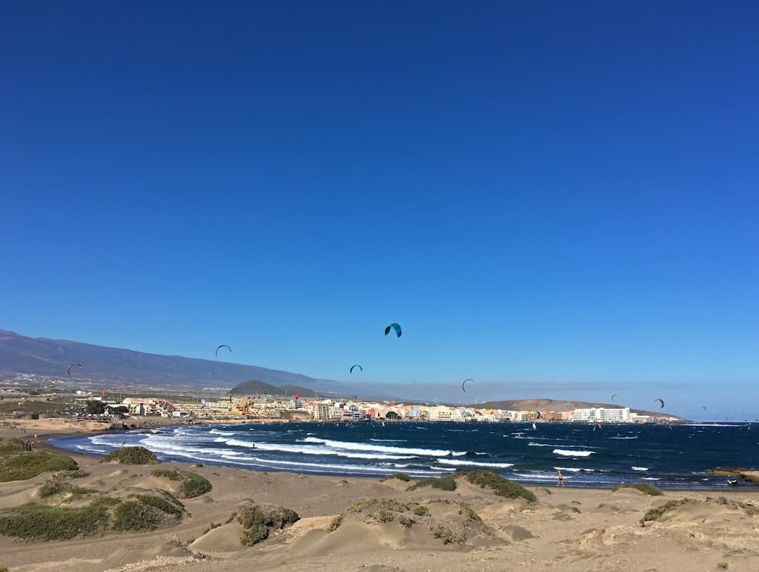 Kitesurfing na piaszczystej plaży przy nadmorskim miasteczku.