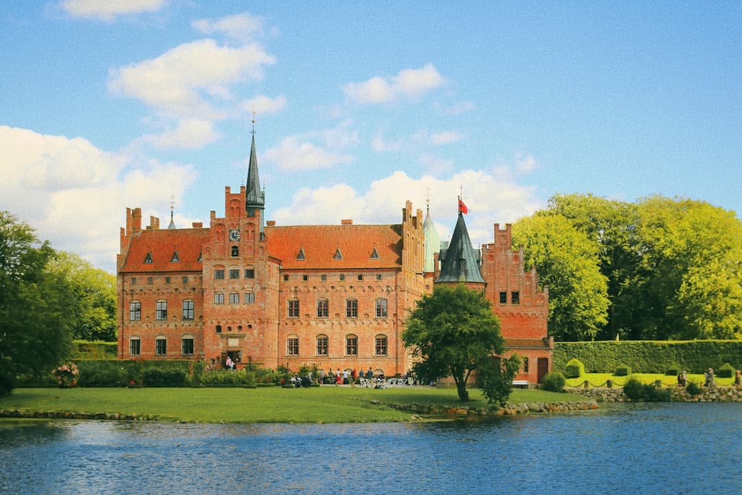 Zabytkowy zamek ceglany z wieżami nad jeziorem.